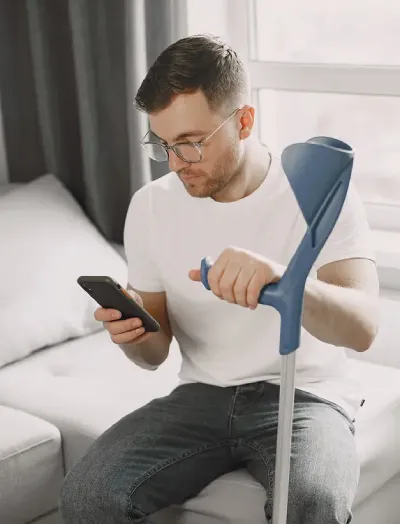 young-man-with-broken-leg-home-using-smartphone